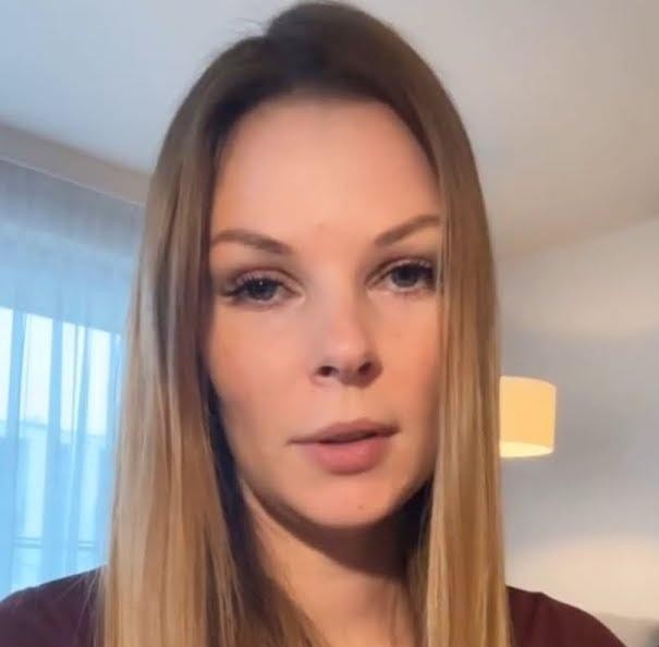 Małgorzata Tomaszewska przeglądająca media społecznościowe na smartfonie, uśmiechnięta.