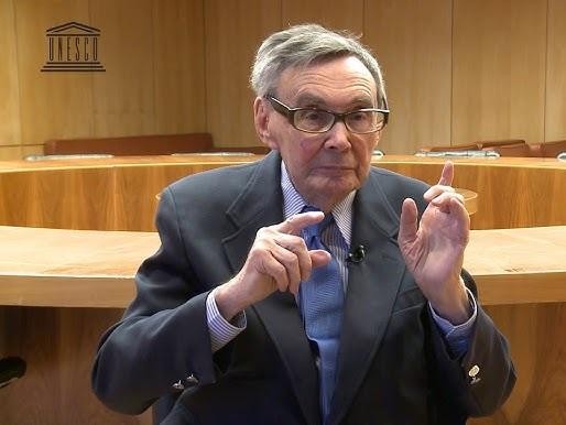 Marian Turski przemawiający, z mikrofonem przed sobą, podczas obchodów rocznicy wyzwolenia Auschwitz, wyrażający poruszające przesłanie o pamięci i historii.