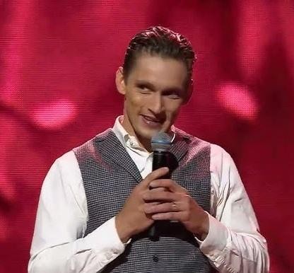 Filip Gurłacz uśmiecha się, patrząc wprost na widza, z rozmytym tłem sugerującym jego aktywność na Instagramie i zaangażowanie z fanami.
