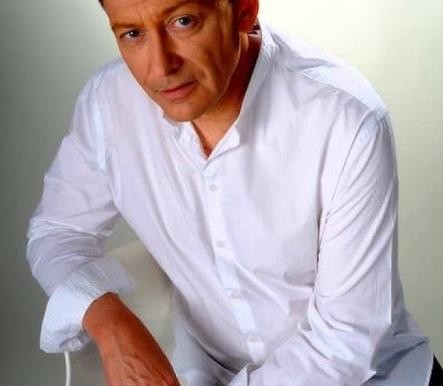 Jacek Borkowski, polski aktor i wokalista, ujęty w dynamicznym kadrze, z tłem sugerującym jego wszechstronną karierę sceniczną i filmową.