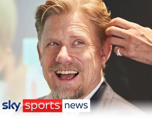 Peter Schmeichel świętujący zwycięstwo w stroju Manchesteru United, z uniesionymi rękami i uśmiechem, w otoczeniu kolegów z drużyny.