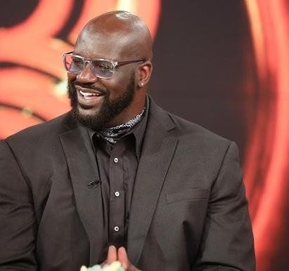 Shaquille O'Neal podczas meczu koszykówki, w dynamicznej pozie, prezentujący swoją dominującą siłę i skupienie na boisku.