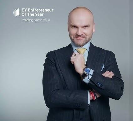 Rafał Brzoska w otoczeniu paczkomatów InPost, symbolizujący innowacje w logistyce i osiągnięcia w karierze.