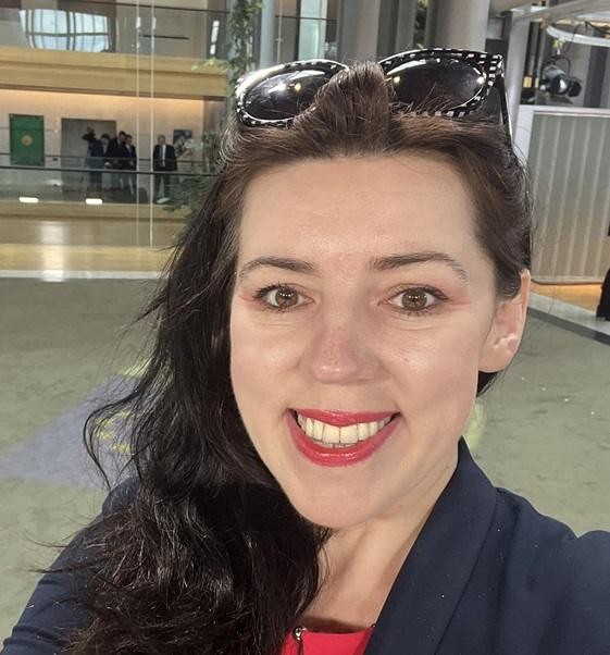 Dominika Ćosić przemawiająca podczas konferencji lub debaty, podkreślająca jej rolę jako ekspertki i publicystki międzynarodowej.