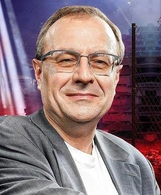 Antoni Dudek podczas wykładu lub publicznego wystąpienia, z ekranem prezentującym treści historyczne w tle.