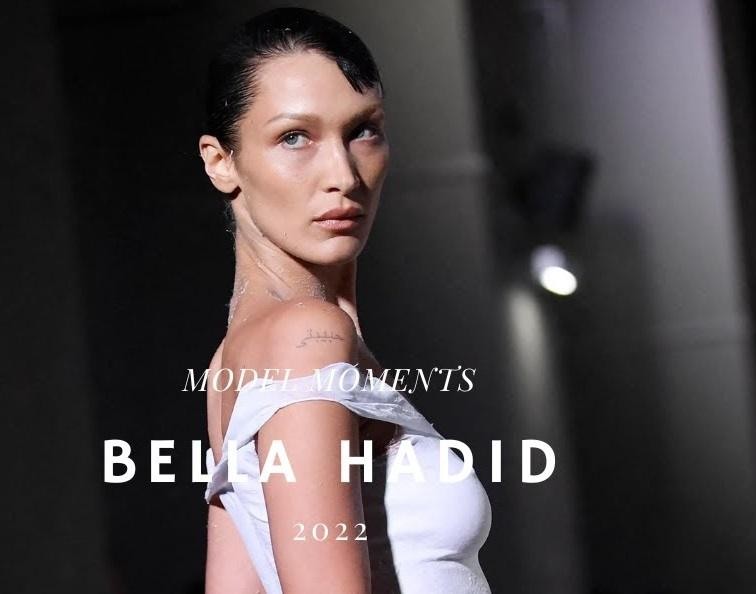 Bella Hadid na wybiegu podczas pokazu mody, w dynamicznej pozie, prezentująca awangardową stylizację.