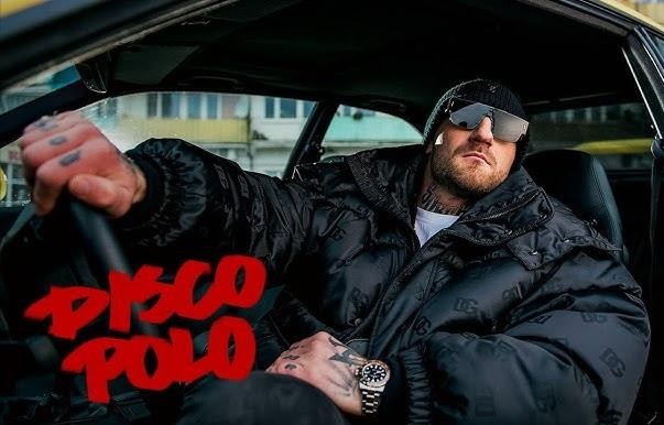 Kizo na ringu MMA, w dynamicznej pozie, podkreślającej jego zaangażowanie w sporty walki i siłę fizyczną.